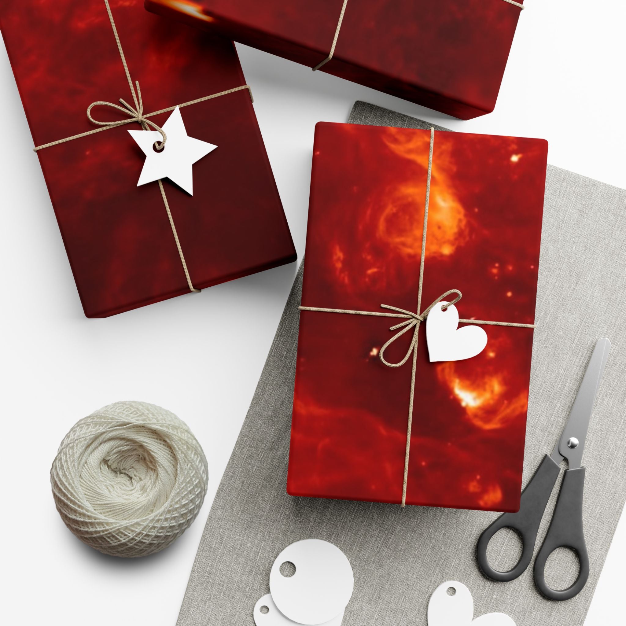 Red gift boxes with decorative tags and scissors on a white surface