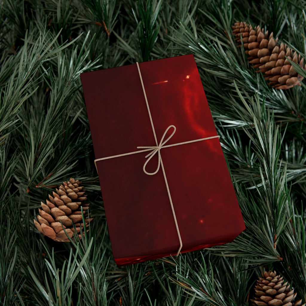 Red gift box with string bow on a bed of pine needles and pine cones