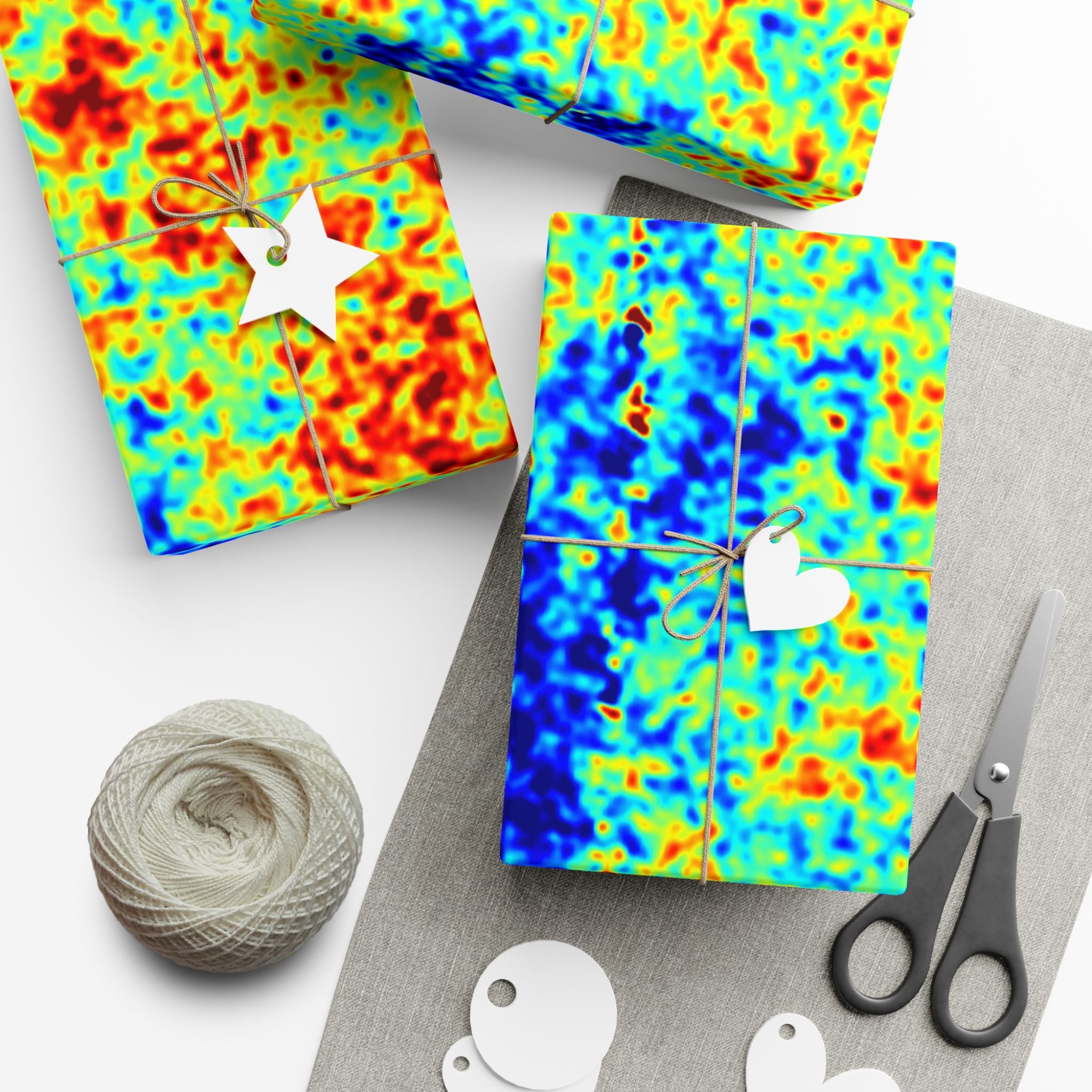 Colorful cosmic microwave backround pattern gift wrap with scissors and yarn on a white surface