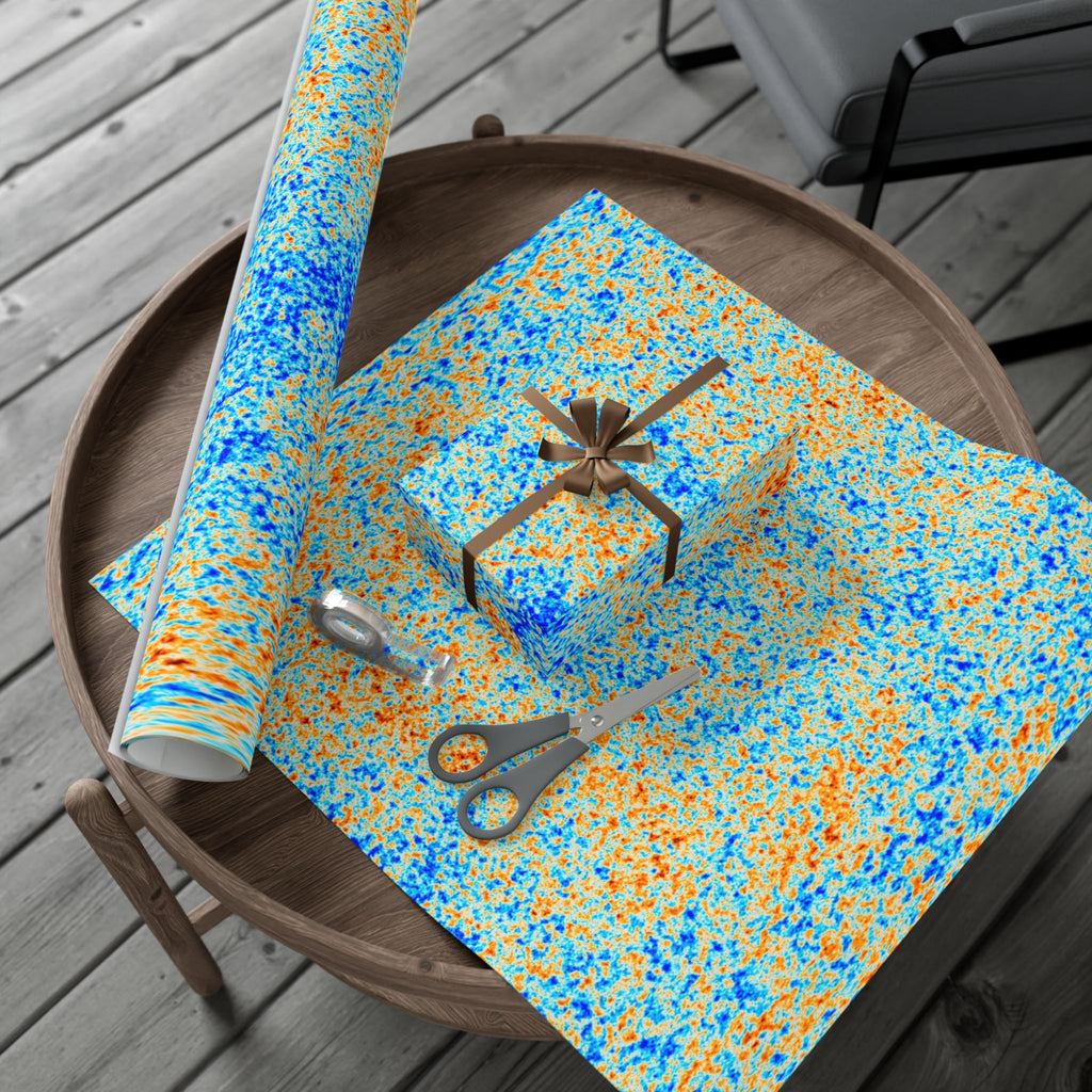 Spotted pattern of Cosmic Microwave Background on wrapping paper with scissors on a wooden table